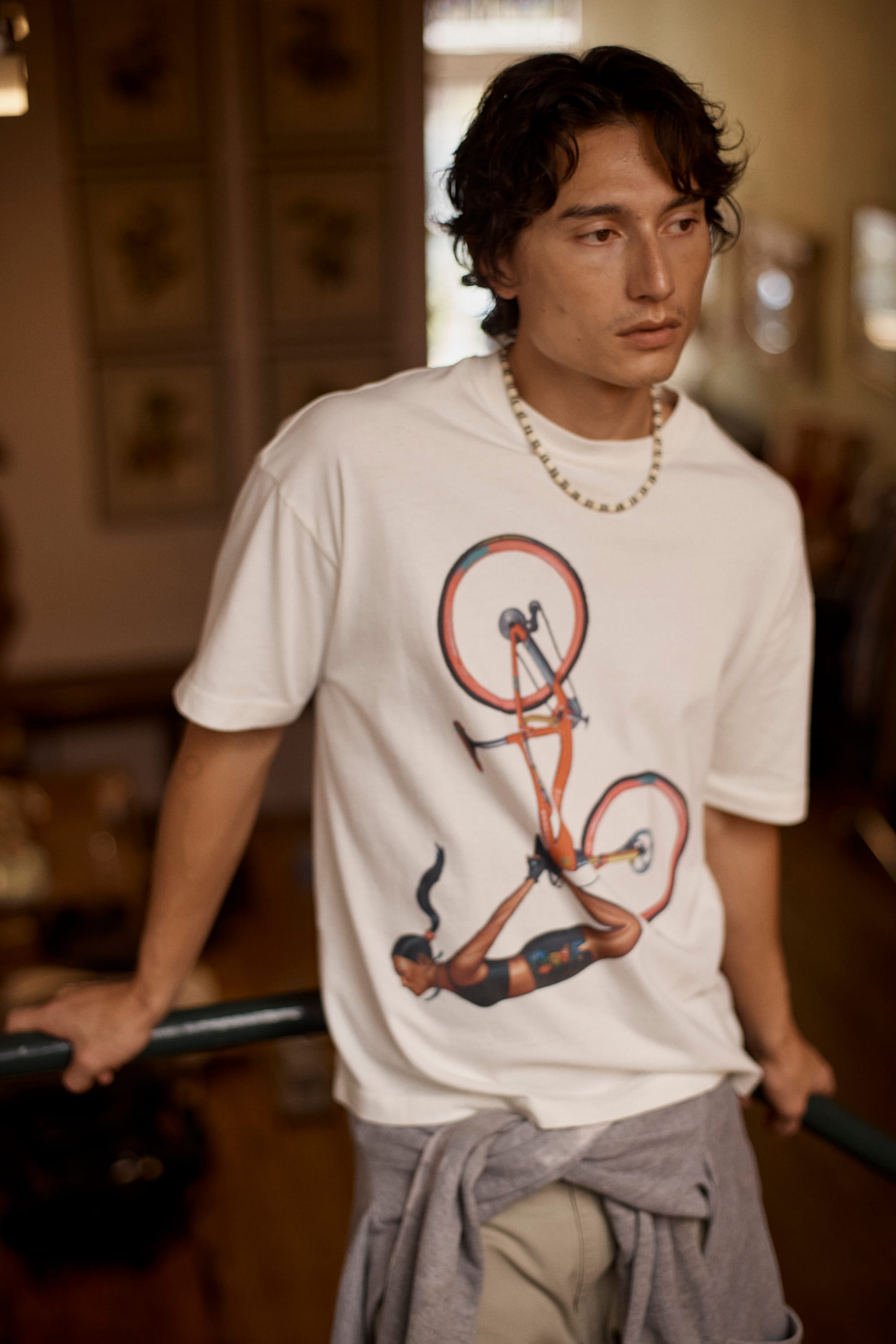 Model wearing a Hosh graphic T-shirt featuring artist-designed artwork, photographed indoors.