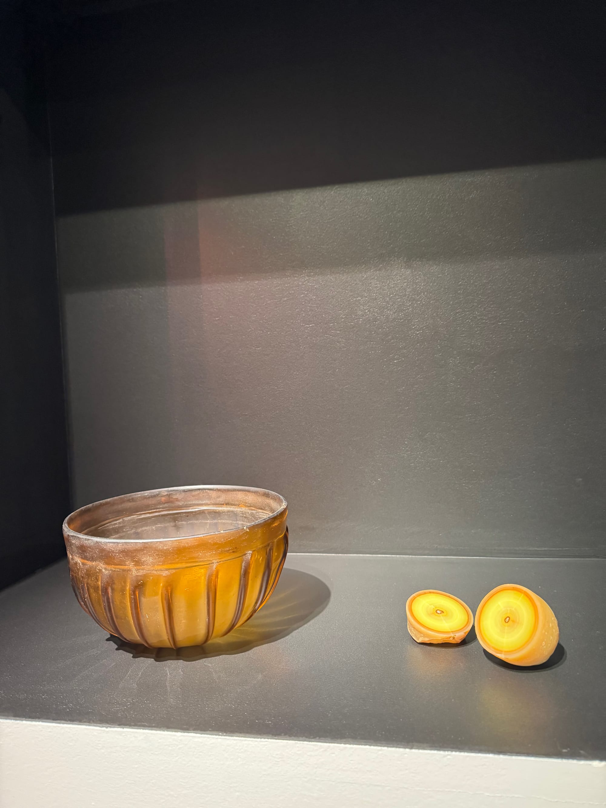 A complete slice of cadmium smithsonite, right, from the Masua Mine in Sardinia, Italy, is pictured next to an ancient bowl