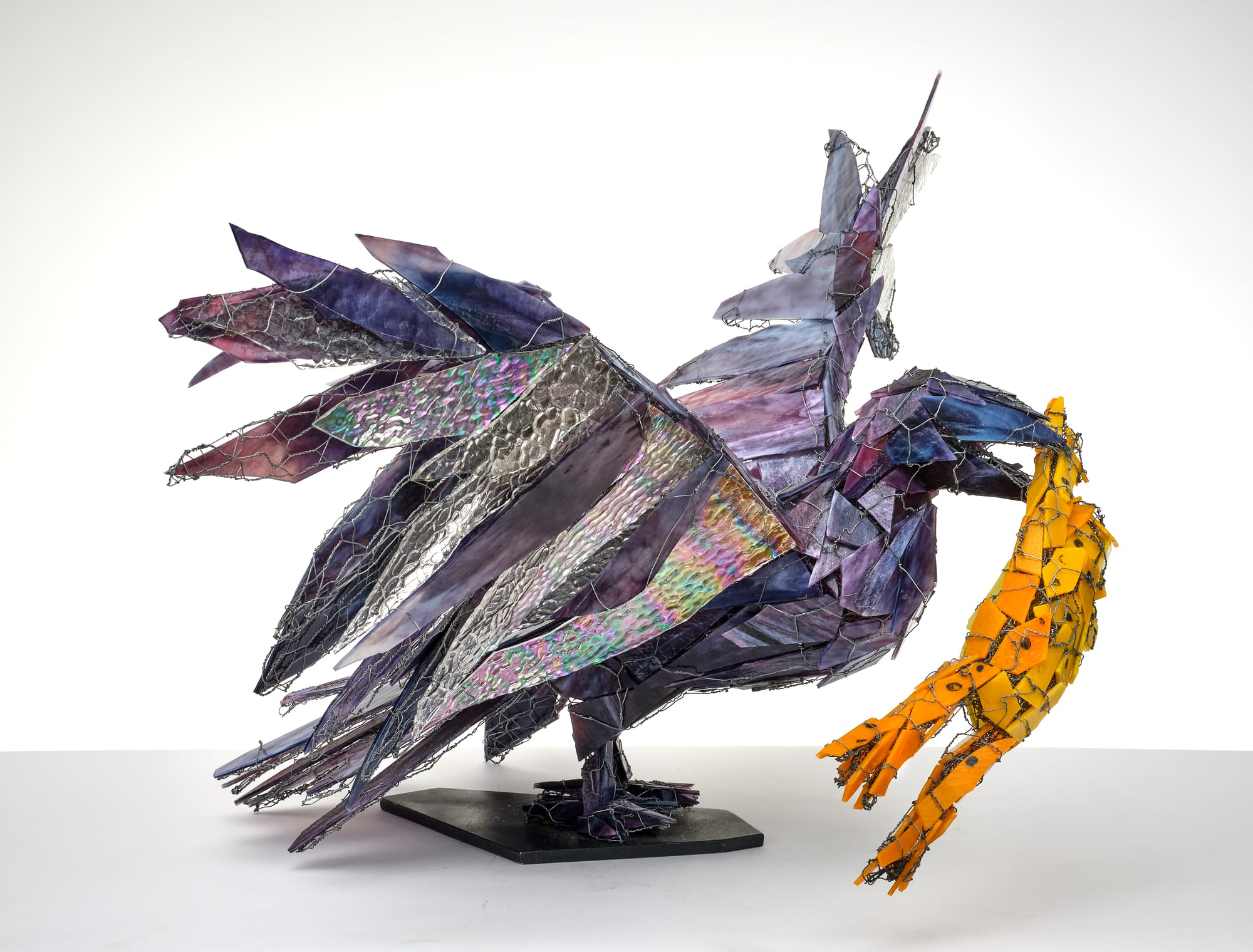 A glass sculpture of a raven with a frog in its mouth