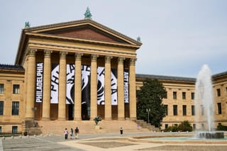 The Philadelphia Art Museum building with large black-and-white banners displaying its new logo and name hanging between the front columns.