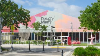 An external view of the Design Miami fair in 2023 as people walk past sculptures outside the tent.