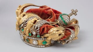 Jeweled gold crown with emeralds and diamonds, featuring eagle motifs and detachable ornaments, photographed against a neutral background.