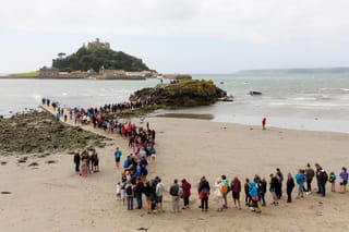 A photograph by Martin Parr depicting people lining up to cross the causeway to St. Michael’s Mount in Cornwall, England