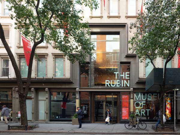 An exterior shot of the Rubin Museum of Art with the museum's name in the windows