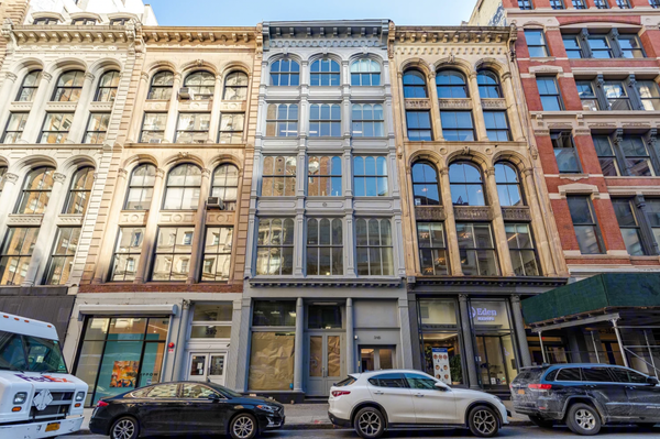 Street view of 390 Broadway in Tribeca, showing a row of historic cast-iron buildings with tall arched windows and parked cars along the curb.