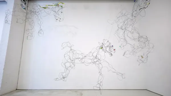 Wire sculpture of galloping horses suspended across a white gallery wall in an SVA MFA exhibition.
