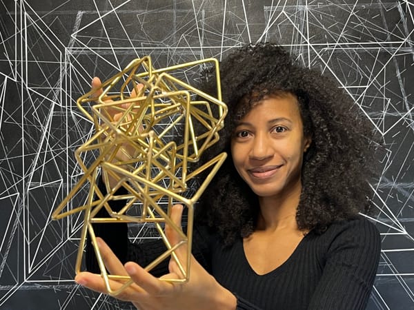 Caroline Gueye holds a gold metallic sculpture.