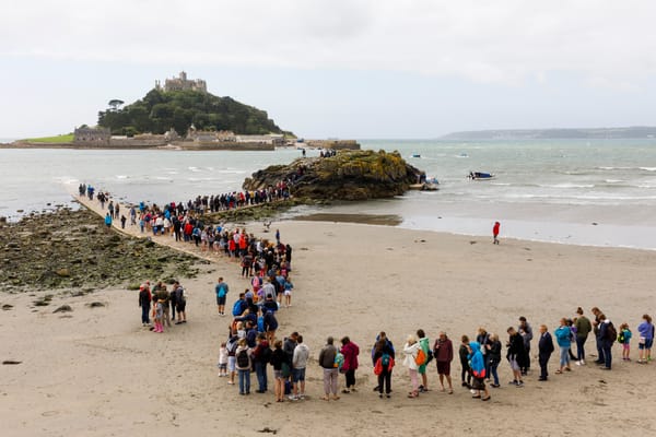 A photograph by Martin Parr depicting people lining up to cross the causeway to St. Michael’s Mount in Cornwall, England